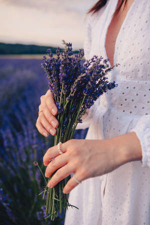 woman in white dress holding bouquet of lavender flowers close upの写真素材