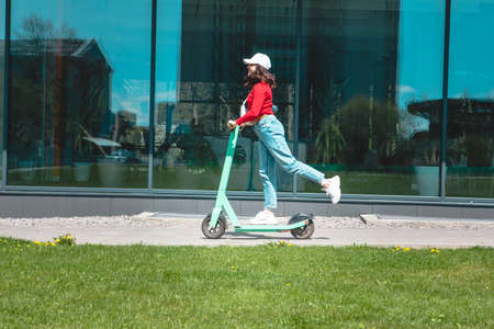 young woman riding electric kick scooter copy space spring sunny dayの写真素材