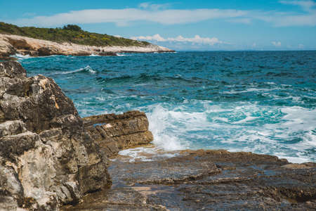 view of water with waves with rocky cliff. copy space