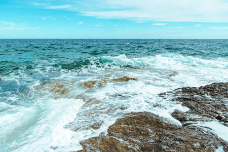 view of rocky seaside waves with white foam. copy space
