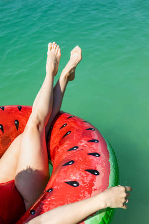 sexy woman legs on inflatable ring floating in blue lake water copy spaceの写真素材