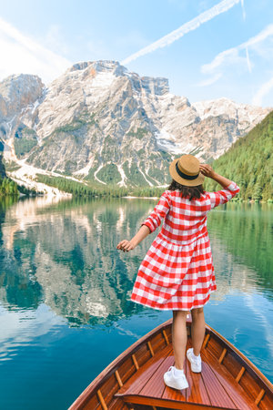 woman sitting in big brown boat at lago di braies lake in Italy. summer vacationの写真素材