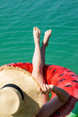 sexy woman legs on inflatable ring floating in blue lake water copy space