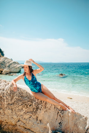 sexy woman in blue swimsuit laying down on the rock at sea beach summer vacationの写真素材