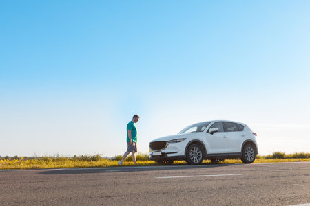 man traveler standing near car at roadside of speedway at sunset copy space
