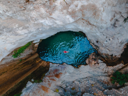 overhead view of dimosari waterfall lake with happy woman floating on the back