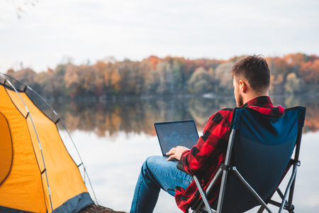 man sitting in chair near autumn lakeの写真素材