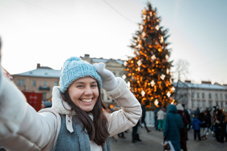 beautiful smiling women taking selfie picture at city square christmas tree on backgroundの写真素材