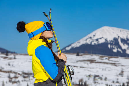 young smiling pretty woman holding ski. mountains on backgroundの写真素材