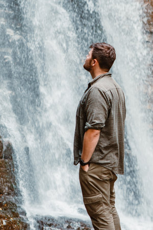 young strong man hiker looking the waterfallの写真素材