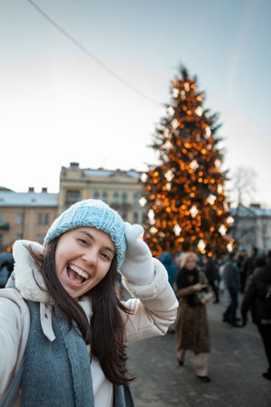 beautiful smiling women taking selfie picture at city square christmas tree on backgroundの写真素材