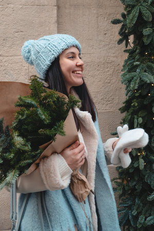 beautiful fashionable woman sitting on the chair at outdoors cafe with christmas tree bouquetの写真素材