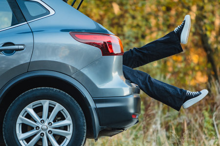 The trunk of a car is full of women whose legs are sticking out. Taking a break after a long driveの写真素材