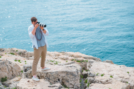 man with professional dslr camera taking picture of seashoreの写真素材