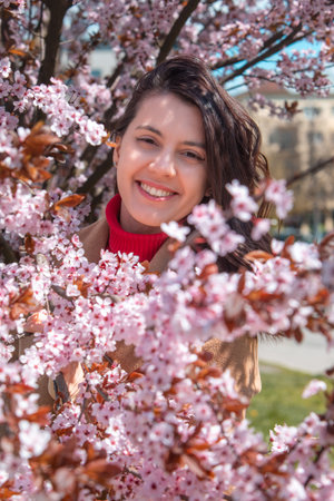 woman taking picture in blooming sakura tree