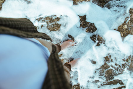 overhead view man barefoot walking by sea rocky beachの写真素材