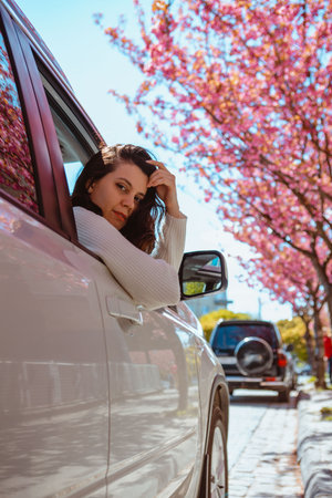 woman get out of the car blooming sakura tree on backgroundの写真素材