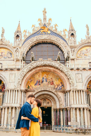 young pretty couple kissing in front of saint marks basilica venice italyの写真素材