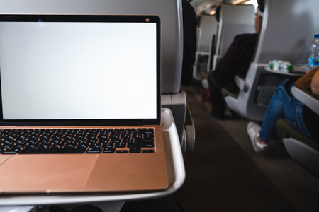 A laptop with a white screen sits on a table in a trainの写真素材