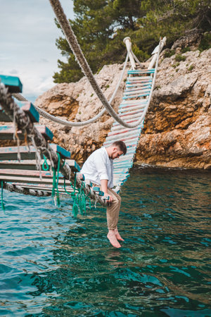 man sitting at suspension bridge enjoying sea view and nature calmnessの写真素材