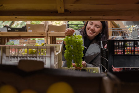 a woman chooses grapes in a storeの写真素材