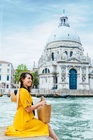 woman in yellow sundress sitting on pier with view of grand canalの写真素材