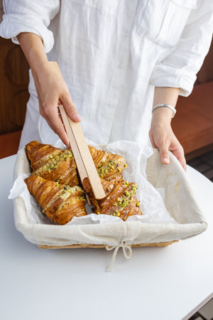 Woman plucks croissant from basket with wooden spikes