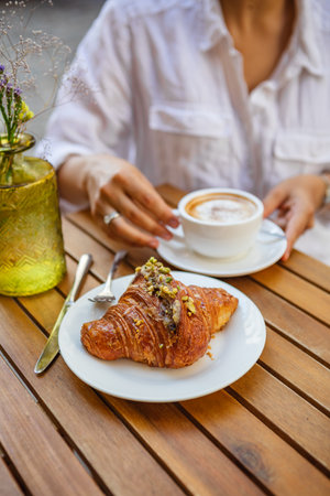 French breakfast made of a croissant and a cup of coffee on the summer terrace in the cafeの写真素材