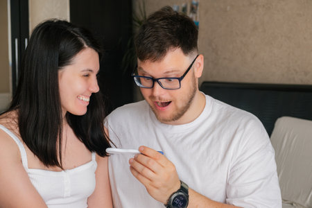 happy couple looking at positive pregnancy testの写真素材