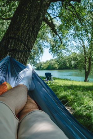 pov man laying down on hammock resting at riversideの写真素材