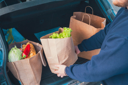 man hands with groceries bags put it in car trunkの写真素材