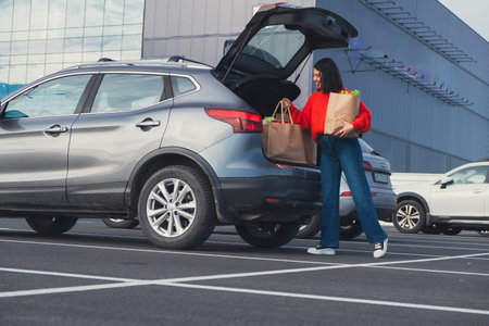 smiling woman put bags in car trunkの写真素材