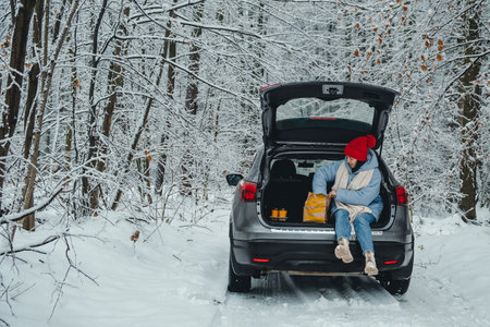 stop for a lunch break. a woman sits in the trunk of her car and takes out food from a package.