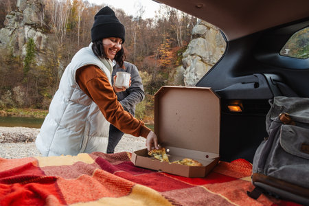 couple sitting in car trunk having picnic resting at nature