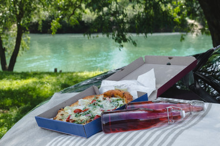 outdoors picnic pizza with drink on car hood at the river sideの写真素材