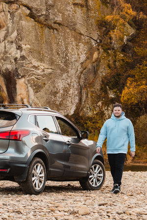man at the rocky beach in mountain river near car