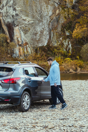 man car traveler stop at river rocky beach enjoying the autumn forestの写真素材