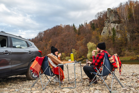 couple having picnic at autumn mountain riverの写真素材