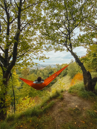 happy man chilling in hammock looking at autumn parkの写真素材