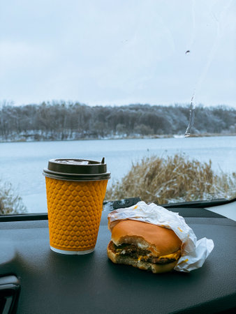 burger and coffee mug at car dashboard