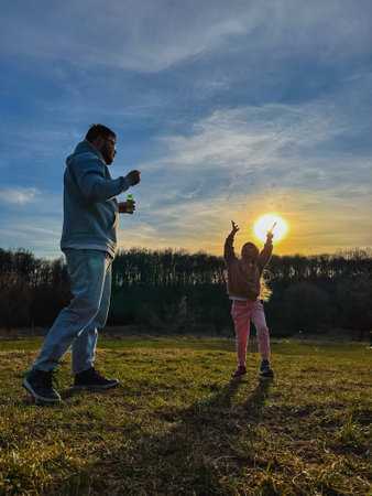 happy man with little girl playing with soap bubbles