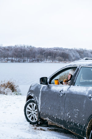 woman eat burger sitting in car at the frozen lake beachの写真素材