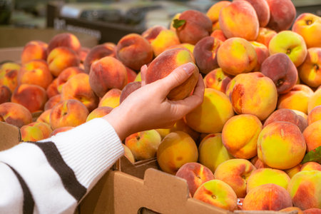 hand taking peach from grocery store shelf