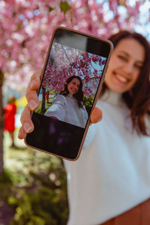 woman shooting her self on the phone under blooming sakura tree