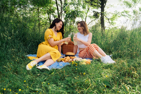 a couple of women on a blue blanket outdoors on a picnicの写真素材
