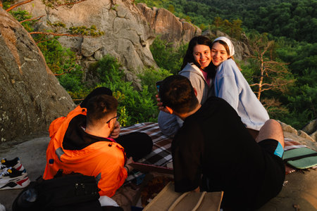 happy friends eating pizza at the cliff with beautiful mountain view