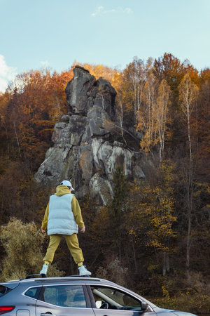 happy woman at car roof enjoying the view of autumn river in carpathian mountains