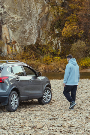 man car traveler stop at river rocky beach enjoying the autumn forest