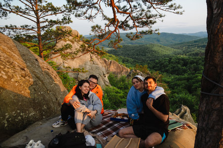 happy friends eating pizza at the cliff with beautiful mountain viewの写真素材