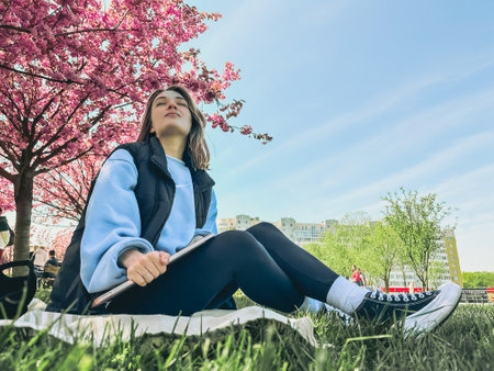 pretty smiling woman posing in front of blooming sakura trees
